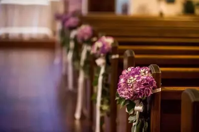 purple flowers on pews along aisle in wedding chapel