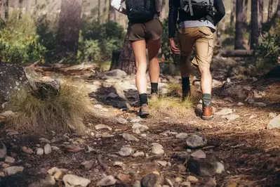 two hikers walking on a trail in the mountains